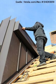 Spengler/Dachdecker führt Dacharbeiten an einer Gaube durch. 
